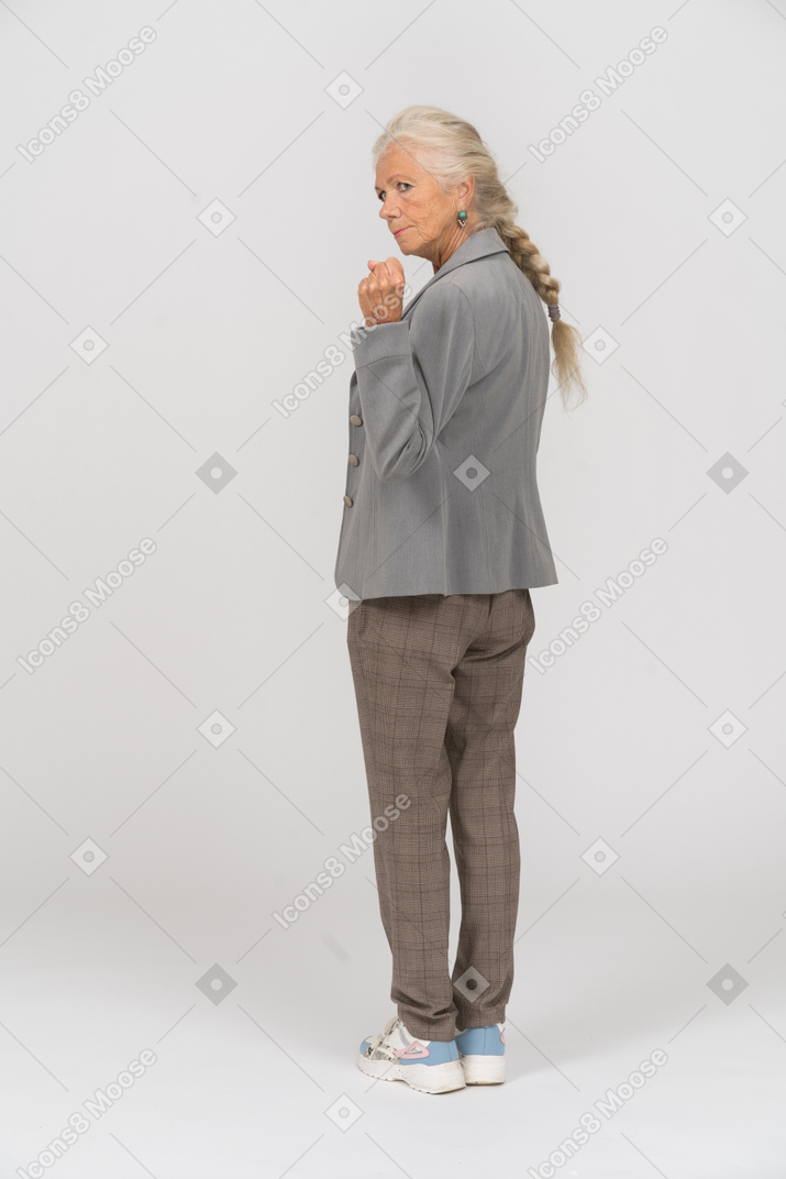一个穿着西装的愤怒老妇人的后视图显示拳头