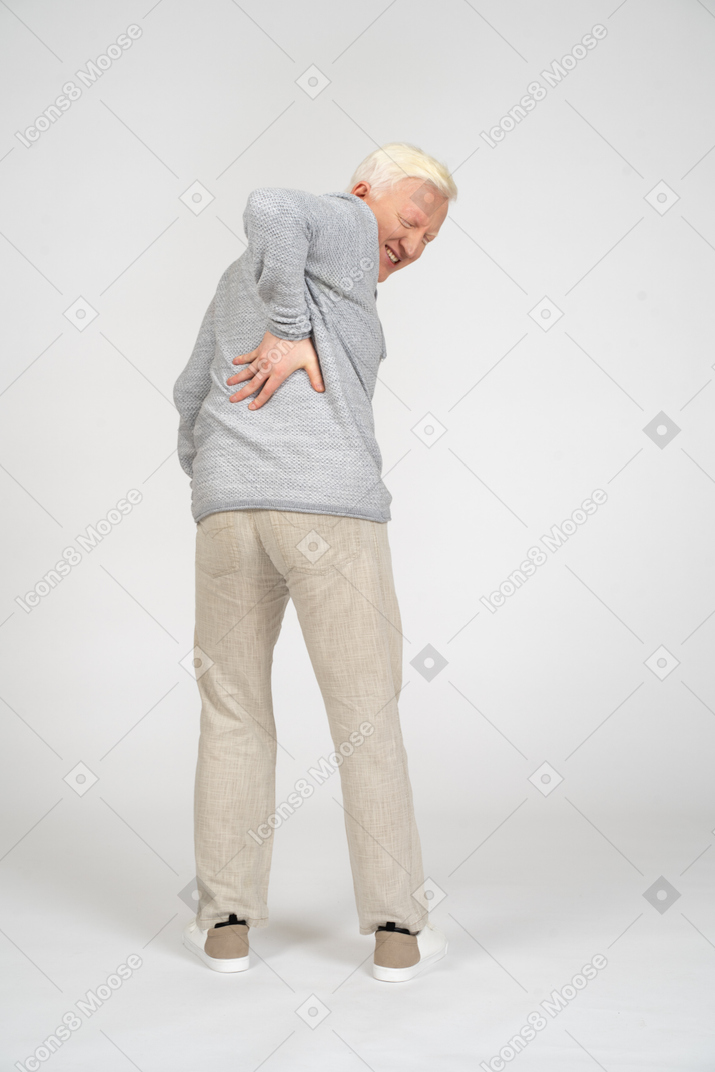 Back view of man holding his hand on his lower back