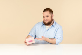 Grande homem sentado à mesa e segurando a lancheira