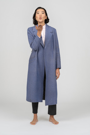 Woman in blue coat blowing a kiss