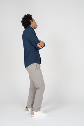 腕を組んで立っているカジュアルな服装の男性の側面図