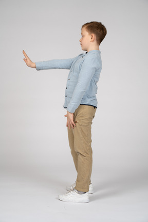 Side view of a boy of a boy standing with extended arm