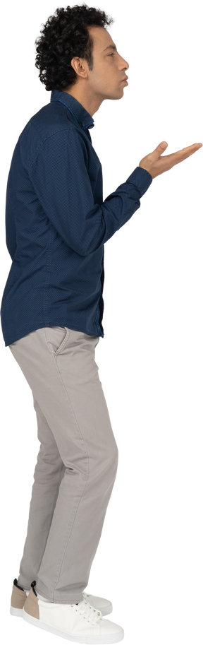 Side view of a man in casual clothes blowing a kiss