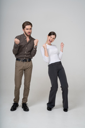 Vista frontal de um jovem casal encantado com roupas de escritório