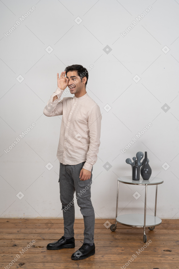 Vista lateral de un hombre en ropa casual mirando a través de los dedos