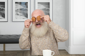 Anciano cubriendo sus ojos con galletas