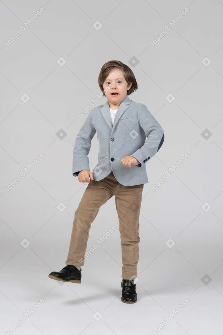 A young boy in a gray jacket tapping his foot