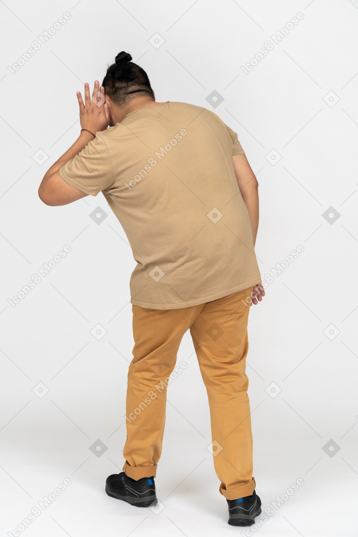 Young man using his palm to hear something