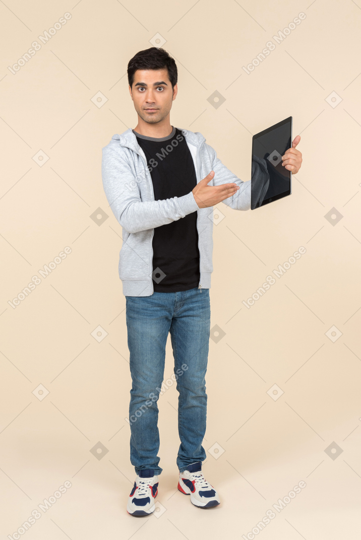 Junger kaukasischer mann, der auf digitale tablette zeigt, die er hält