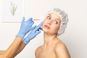 Woman looking terrified during filler injection