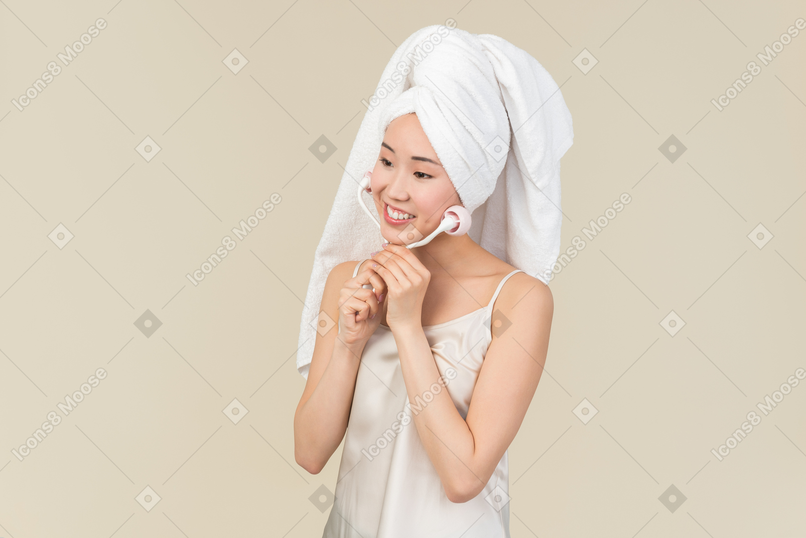 Jovem mulher asiática com cabelo enrolado em toalha fazendo massagem de rosto