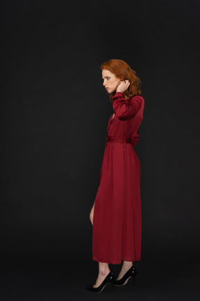 Vista lateral de la joven vestida de rojo y tocando el cabello