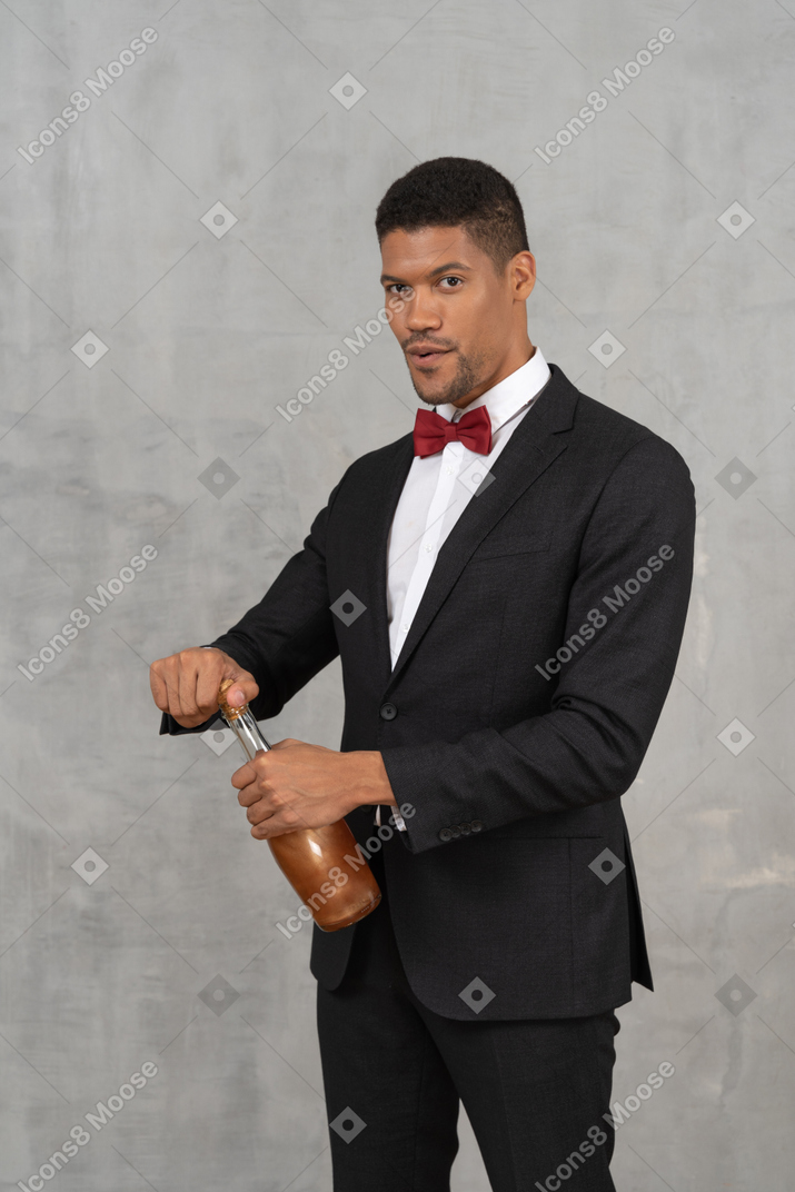 Uomo in abbigliamento formale che apre una bottiglia di alcolici