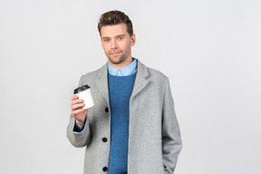 Handsome young guy holding cup of coffee