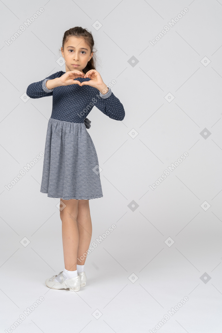 Three-quarter back view of a girl turning and making heart with her hands