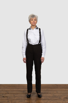 Front view of an old female in office clothes standing still in the room