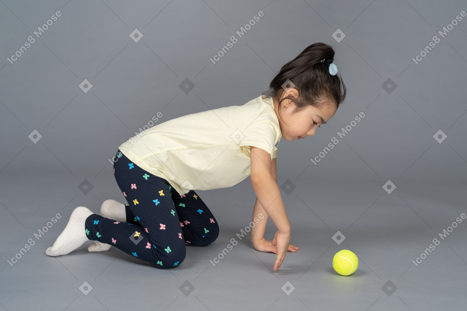 Girl on all fours playing with a tennis ball