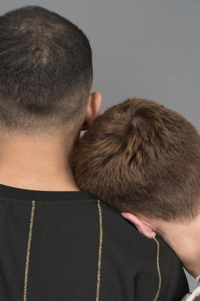 Back view of young man leaning head on boyfriend's shoulder