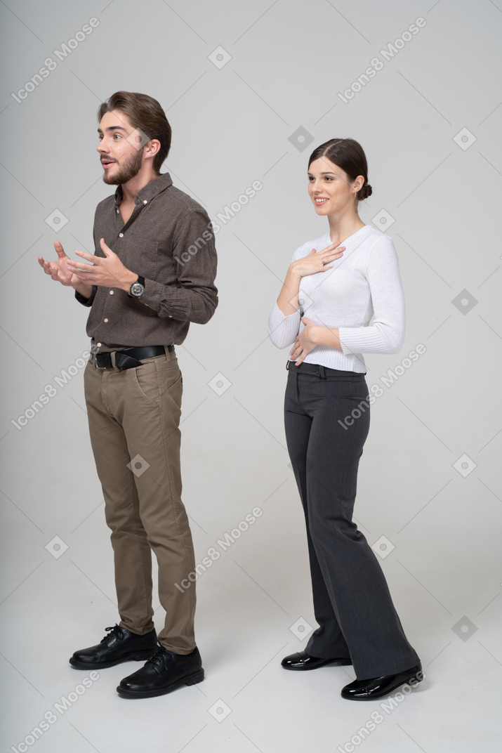 Vista di tre quarti di un giovane uomo interrogativo e una donna soddisfatta in abiti da ufficio