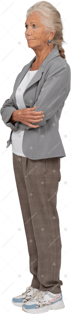 Seitenansicht einer alten dame im anzug, die mit verschränkten armen posiert