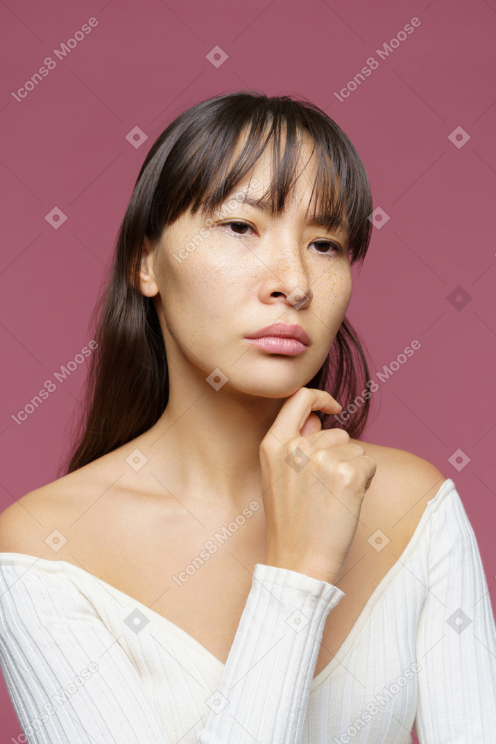 Three-quarter view of a thoughtful middle-aged woman touching chin and looking aside
