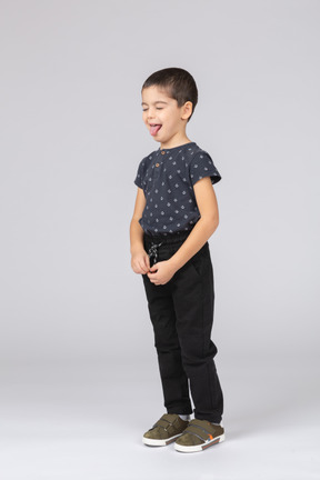 Милый мальчик в повседневной одежде показывает язык