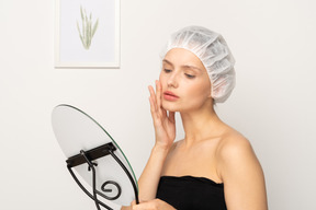 Mujer joven con gorra médica mirándose en el espejo