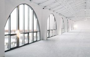 A big empty white hall with a row of big arch windows