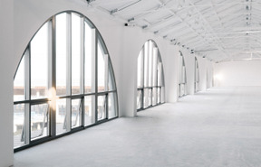 Une grande salle blanche vide avec une rangée de grandes fenêtres en arc