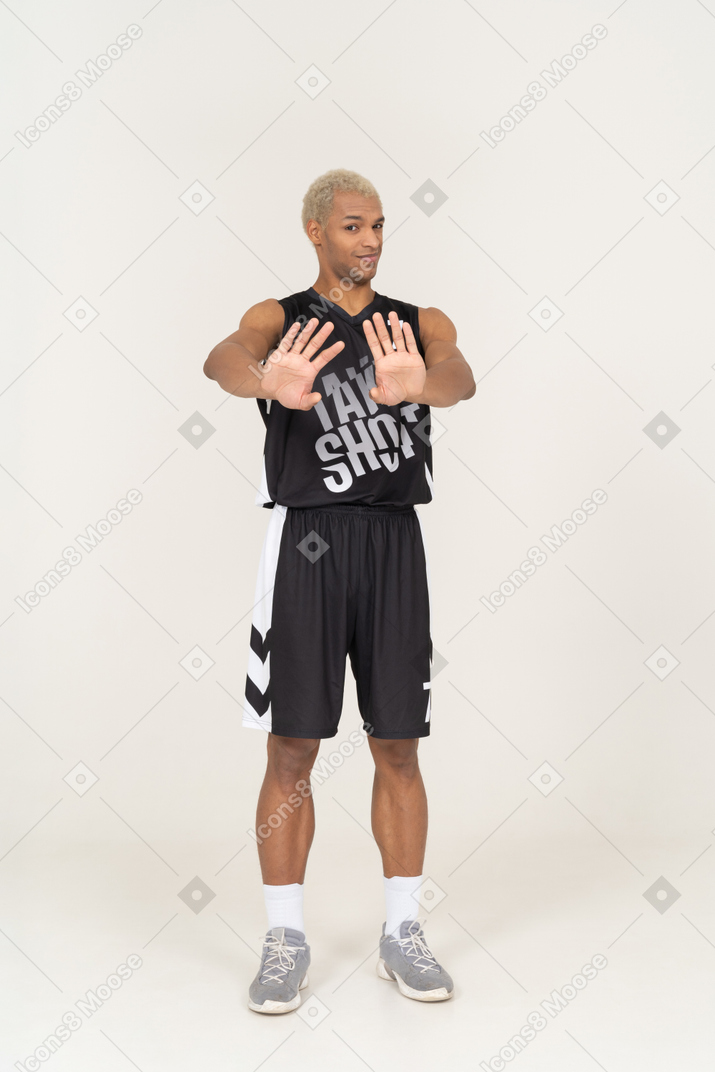 Vista frontale di un giovane giocatore di basket maschile che si rifiuta di allungare le braccia