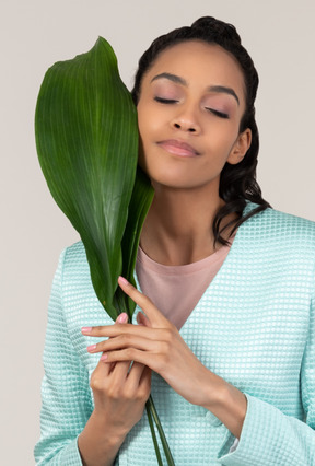 Giovane donna che tiene grande foglia verde