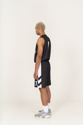 Three-quarter back view of a pouting young male basketball player