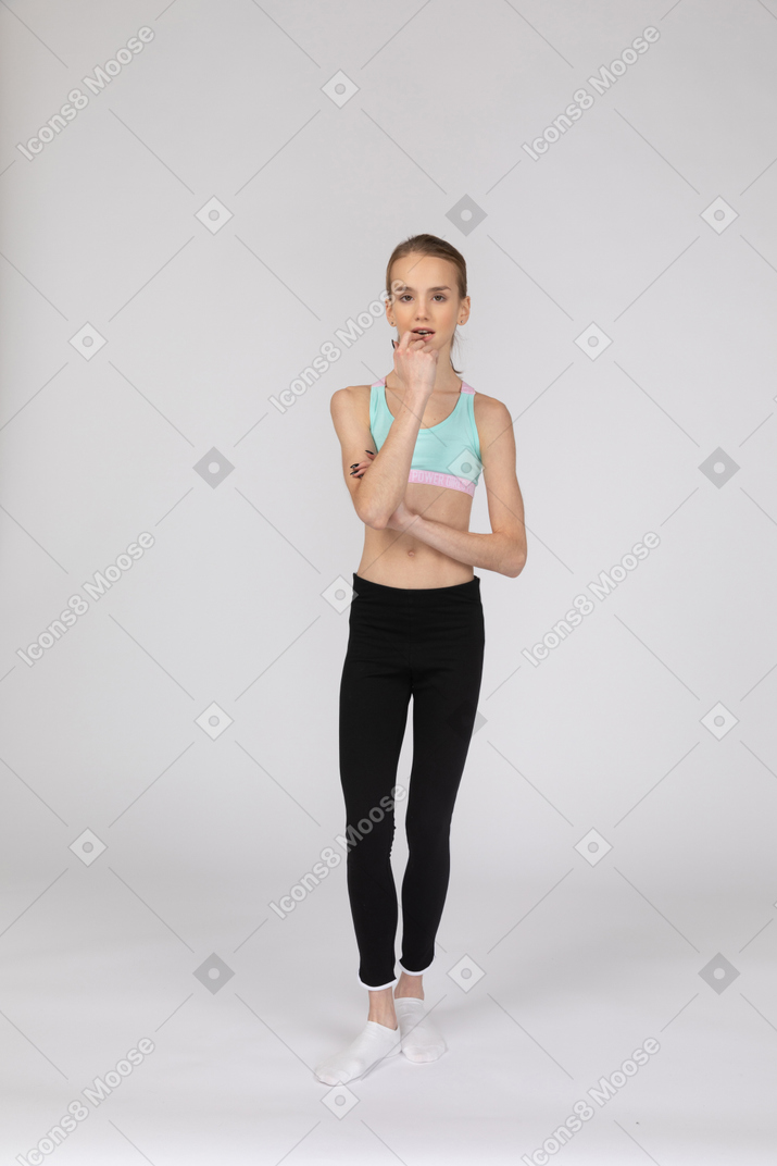 Front view of a thoughtful teen girl in sportswear biting her finger