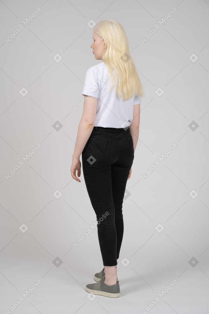 Vista posteriore di tre quarti di una giovane donna bionda in abiti casual