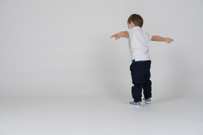 Rear view of a boy standing with his arms outstretched