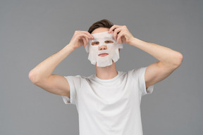 Vista frontal de um jovem colocando máscara facial