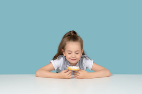 Милая маленькая девочка смотрит на пончик