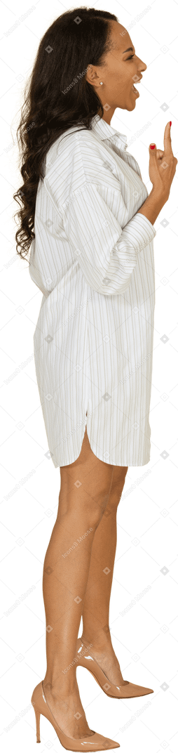 Vista lateral de uma jovem morena cantando em um vestido branco apontando o dedo