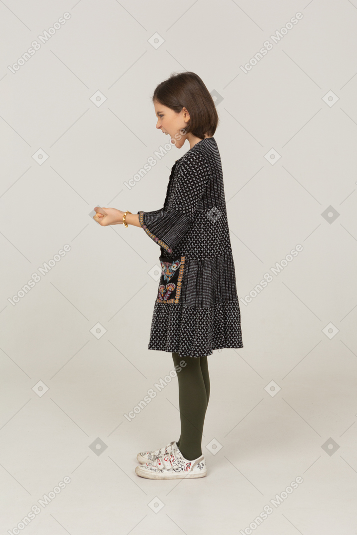 Side view of a furious little girl in dress clenching fists