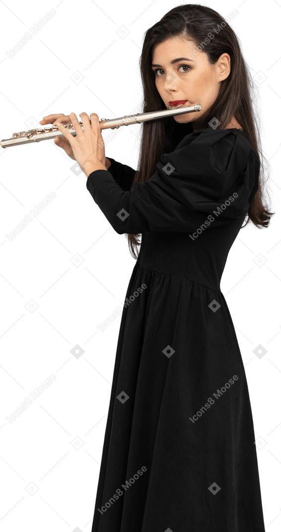 Vista laterale di una giovane donna seria in abito nero che suona il flauto