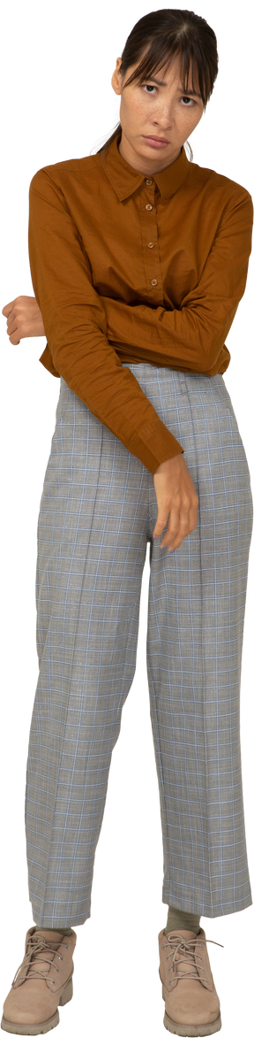 Vista frontale di una giovane donna asiatica ritirata in calzoni e camicetta che tocca lo stomaco