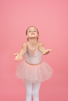 Petite danseuse se penchant en avant avec ses mains allongées et tête en arrière