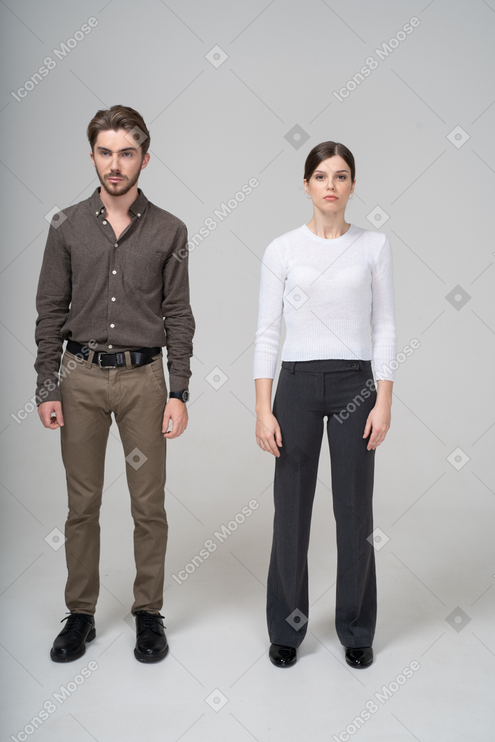 じっと立っているオフィス服を着た若いカップルの正面図