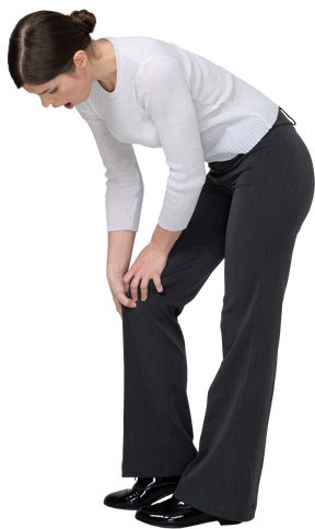 Vista laterale di una giovane donna in abiti da ufficio che tocca il ginocchio