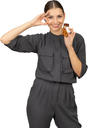 Front view of a young woman in a jumpsuit taking pills out of a jar