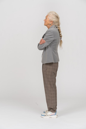 Vista lateral de una anciana en traje posando con los brazos cruzados.