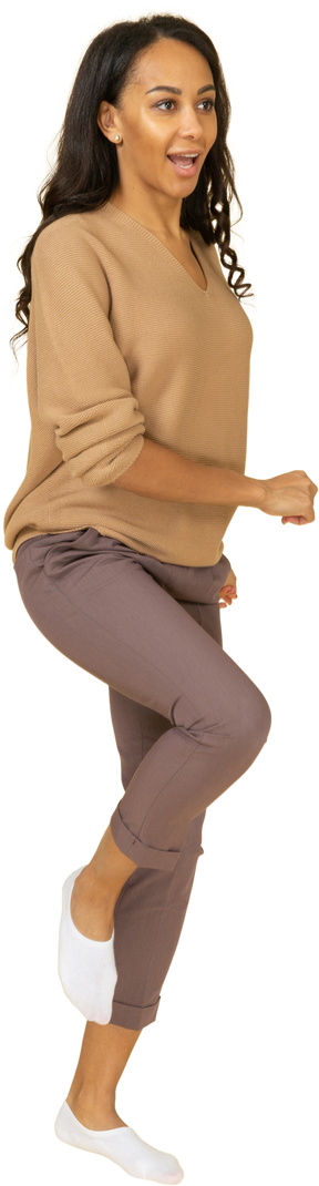 Трехчетвертный вид марширующей темнокожей молодой женщины, поднимающей ногу