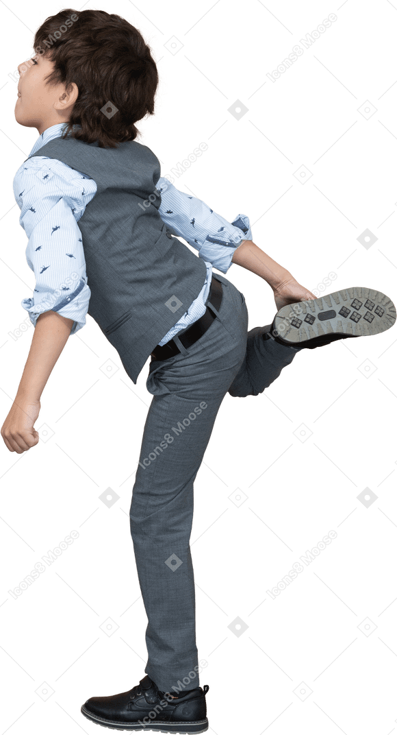 Vista laterale di un ragazzo in abito grigio in piedi su una gamba