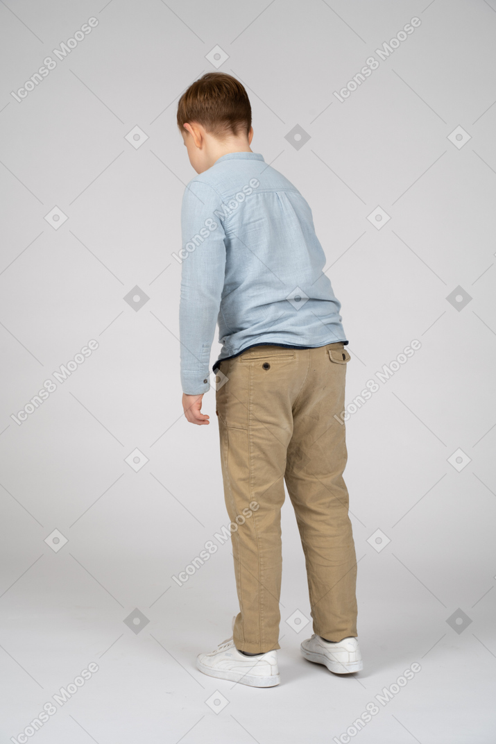 Boy in casual clothes standing back to camera