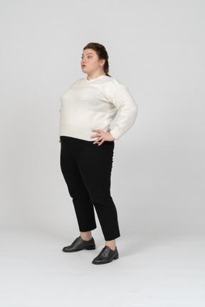Vista laterale di una donna plus size in abiti casual in piedi con le mani sui fianchi